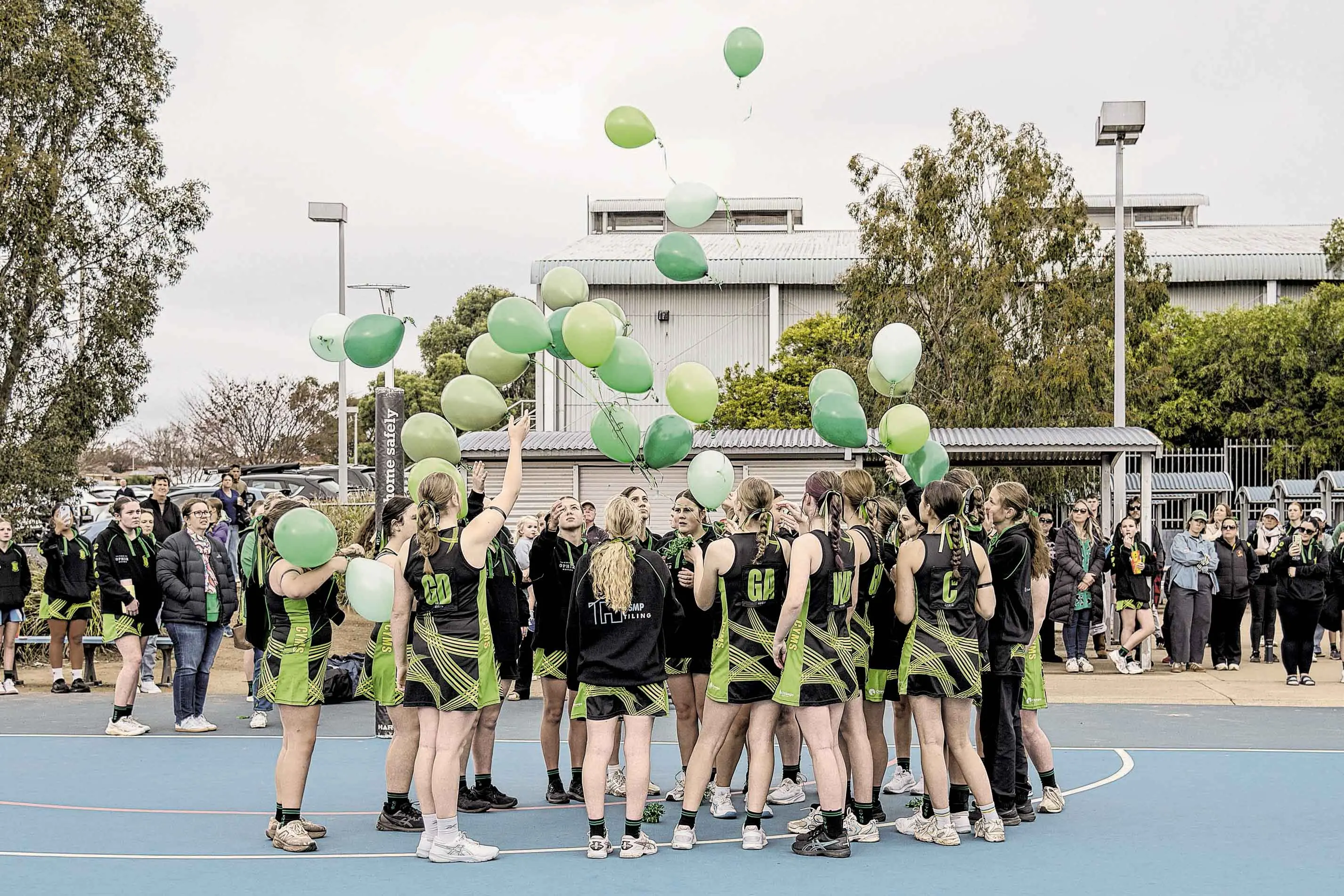 <p>The teammates of Lily Kelly release green balloons in her memory ahead of their game. Photo: Orange City Life. </p>\\n